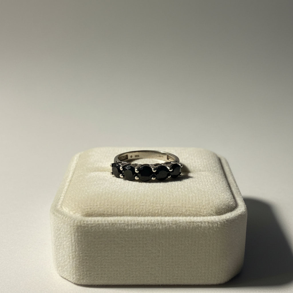 Silver ring with black gemstones on a light gray background