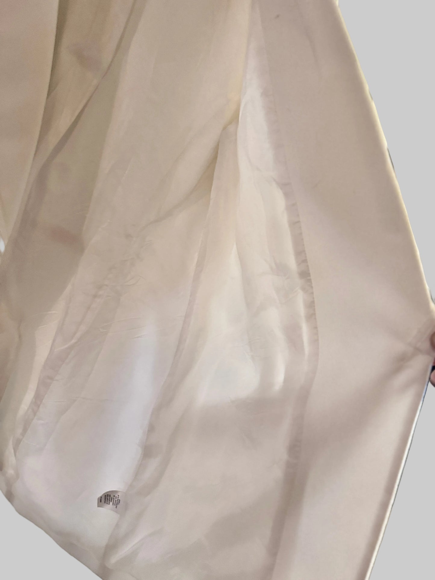 Close-up of a white garment with a brand logo on a blurred background