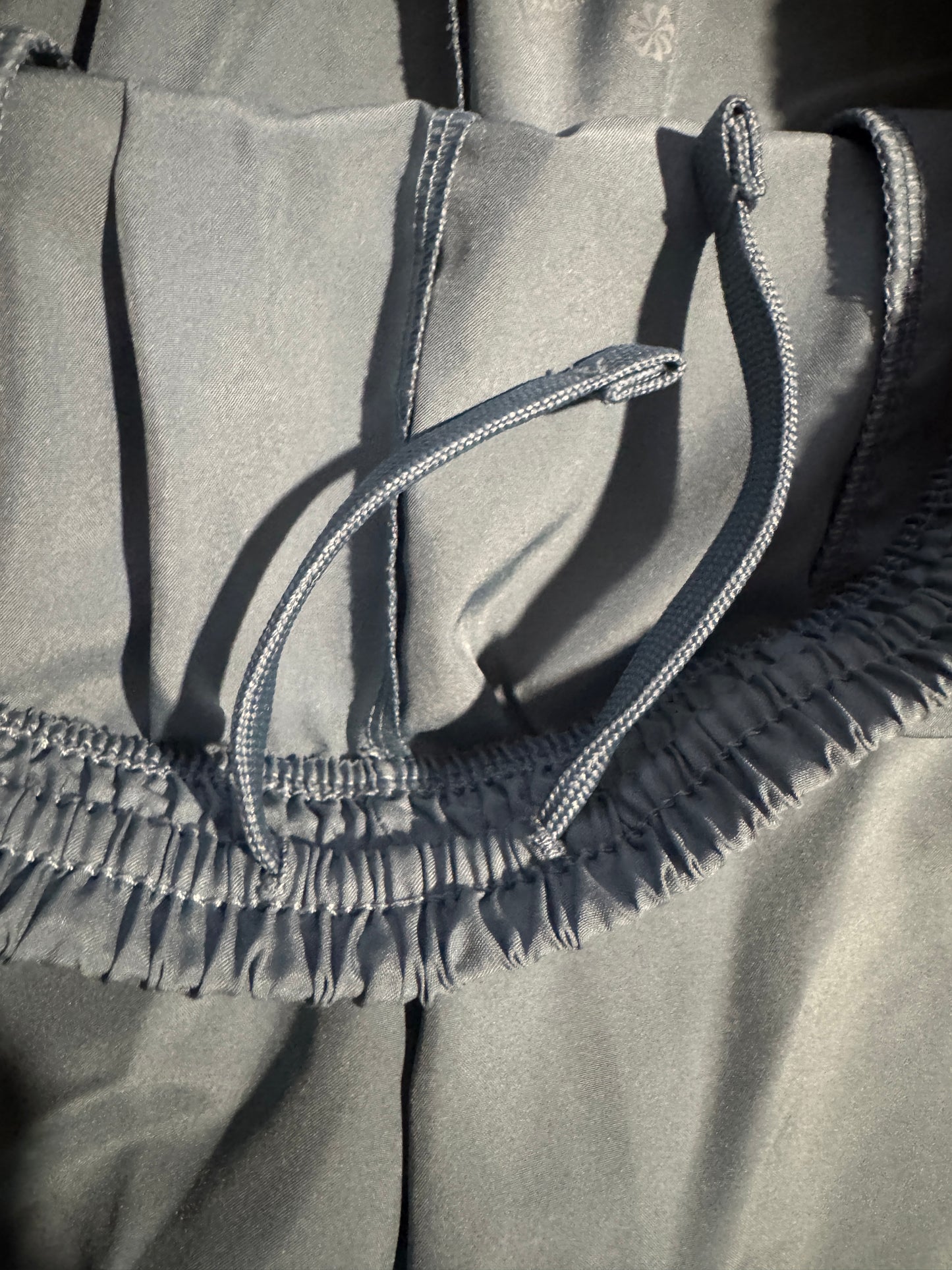 Close-up of gray fabric with a matching drawstring and elasticized gusset detail, showing texture and stitching.