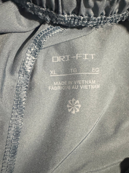 Close-up of the inside waistband of gray athletic pants, showing the elasticized drawstring waist, white printed size and material details, and a white logo.