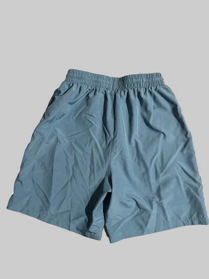 Light blue athletic shorts with an elastic waistband, laid flat on a light-colored wooden surface.