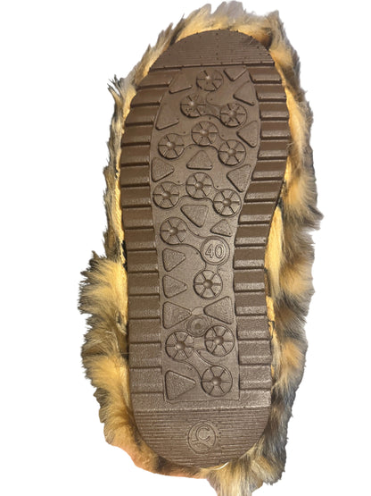 A close-up of a brown rubber shoe sole with tread patterns and a size 40 marking, surrounded by tan and brown faux fur, held up in a home setting.