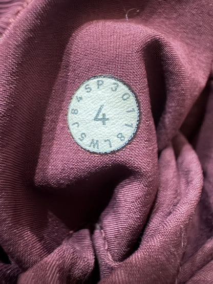 Close-up of a mauve-colored fabric item with a circular white sewn-on size label showing numbers and a size X.