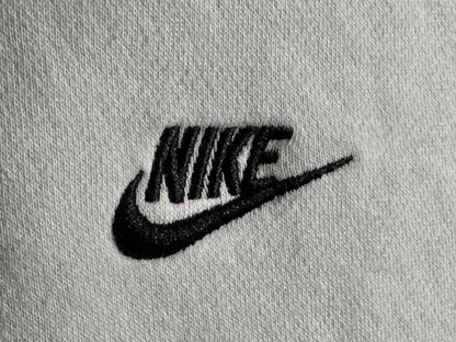 Close-up of a light gray knit fabric with a black embroidered Nike logo and swoosh.