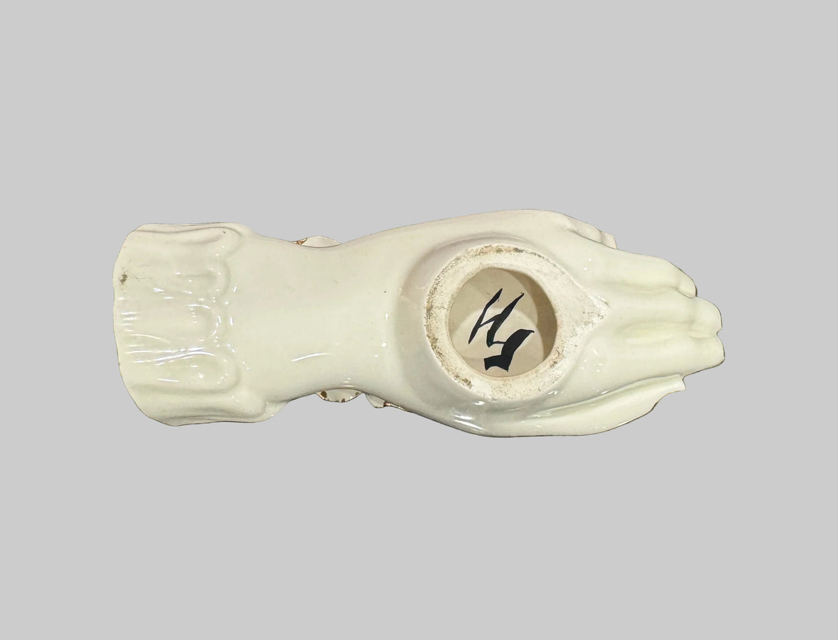 A ceramic hand-shaped jewelry holder with a glossy cream finish, resting on a speckled granite countertop.