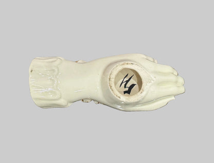 A ceramic hand-shaped jewelry holder with a glossy cream finish, resting on a speckled granite countertop.