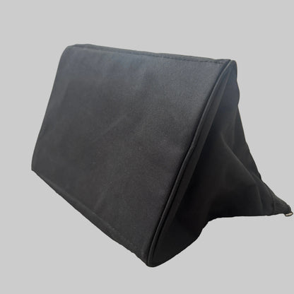 A black triangular wedge-shaped stand made of canvas or fabric, resting on a beige carpeted floor in an indoor setting.