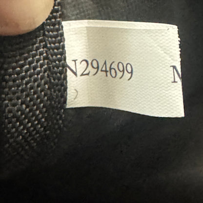 Close-up of a garment's interior neck label showing the printed number N294699 on a white paper tag, next to black knit fabric.