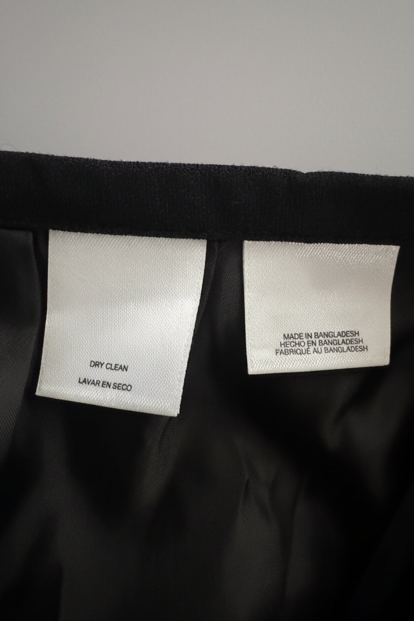 Close-up of the inside neck area of a black garment, showing two white fabric labels. One label reads 'DRY CLEAN' and the other reads 'MADE IN BANGLADESH'.