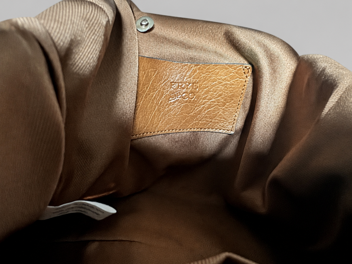 Close-up of a brown satin or silk-like garment interior with a tan leather patch embossed with the brand name Onitsuka Tiger.