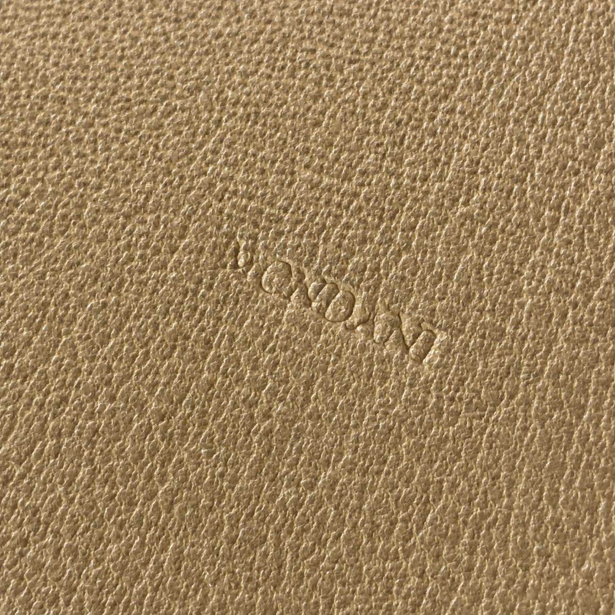 Close-up of a textured tan leather surface with an embossed brand name reading 'Mondani'.