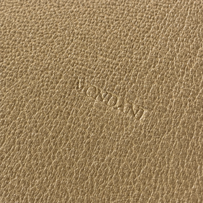 Close-up of a textured tan leather surface with an embossed brand name reading 'Mondani'.