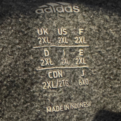 Close-up of a dark gray Adidas garment label showing size conversion information for UK, US, F, D, J, CDN, and MADE IN INDONESIA.