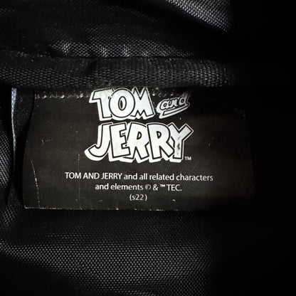 Close-up of a black fabric label with the white 'Tom and Jerry' logo and copyright text sewn onto black woven material.