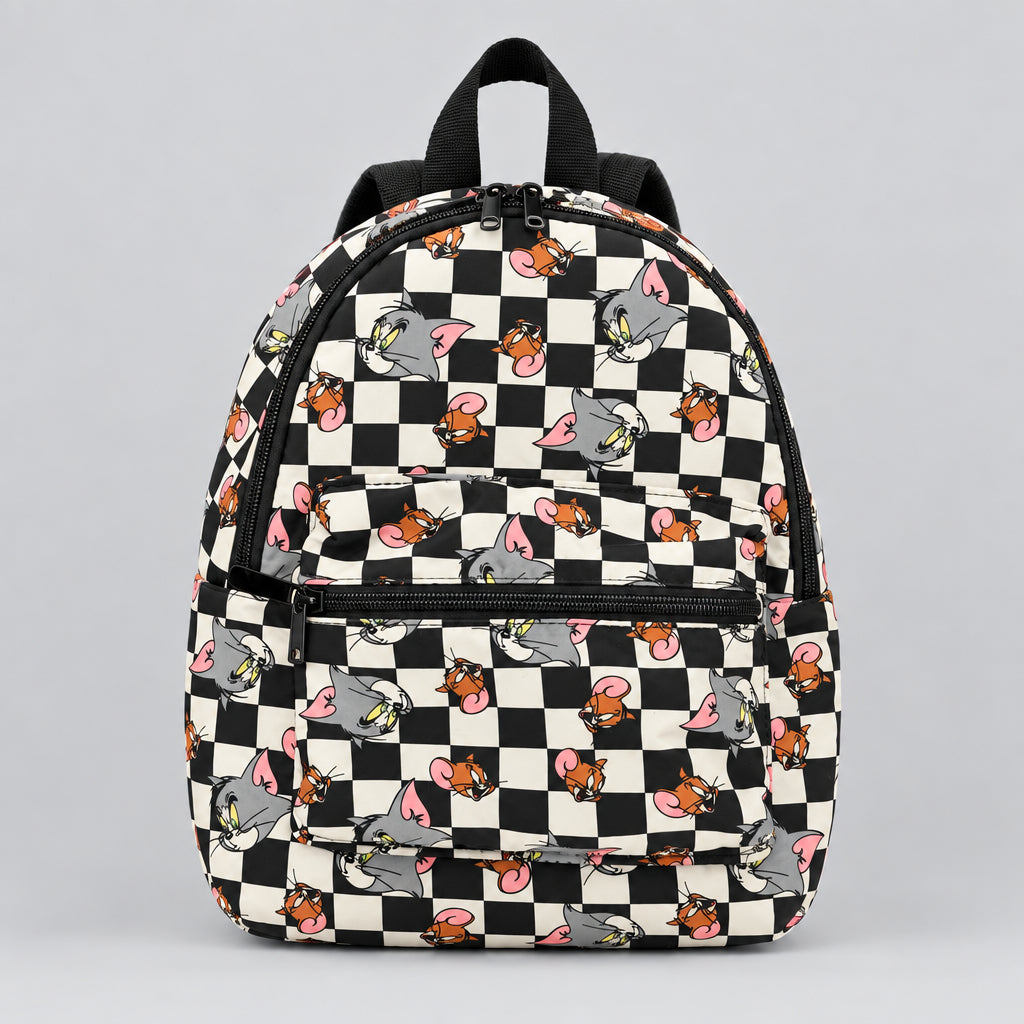A small backpack with a black and cream checkerboard pattern and cartoon mouse graphics, placed on a dark wooden table next to a yellow measuring tape.