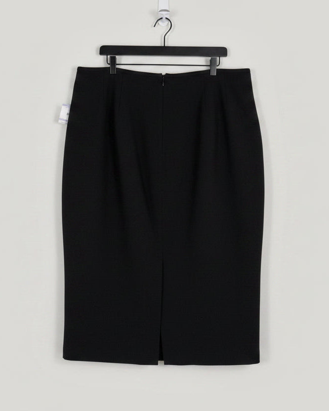 A black knee-length skirt with a front slit, hanging on a black hanger against a white door. A product tag is visible on the left side.