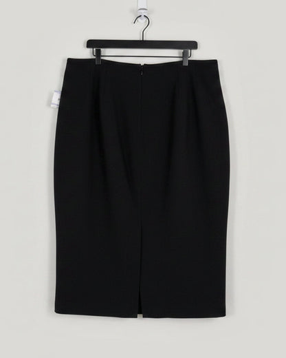 A black knee-length skirt with a front slit, hanging on a black hanger against a white door. A product tag is visible on the left side.