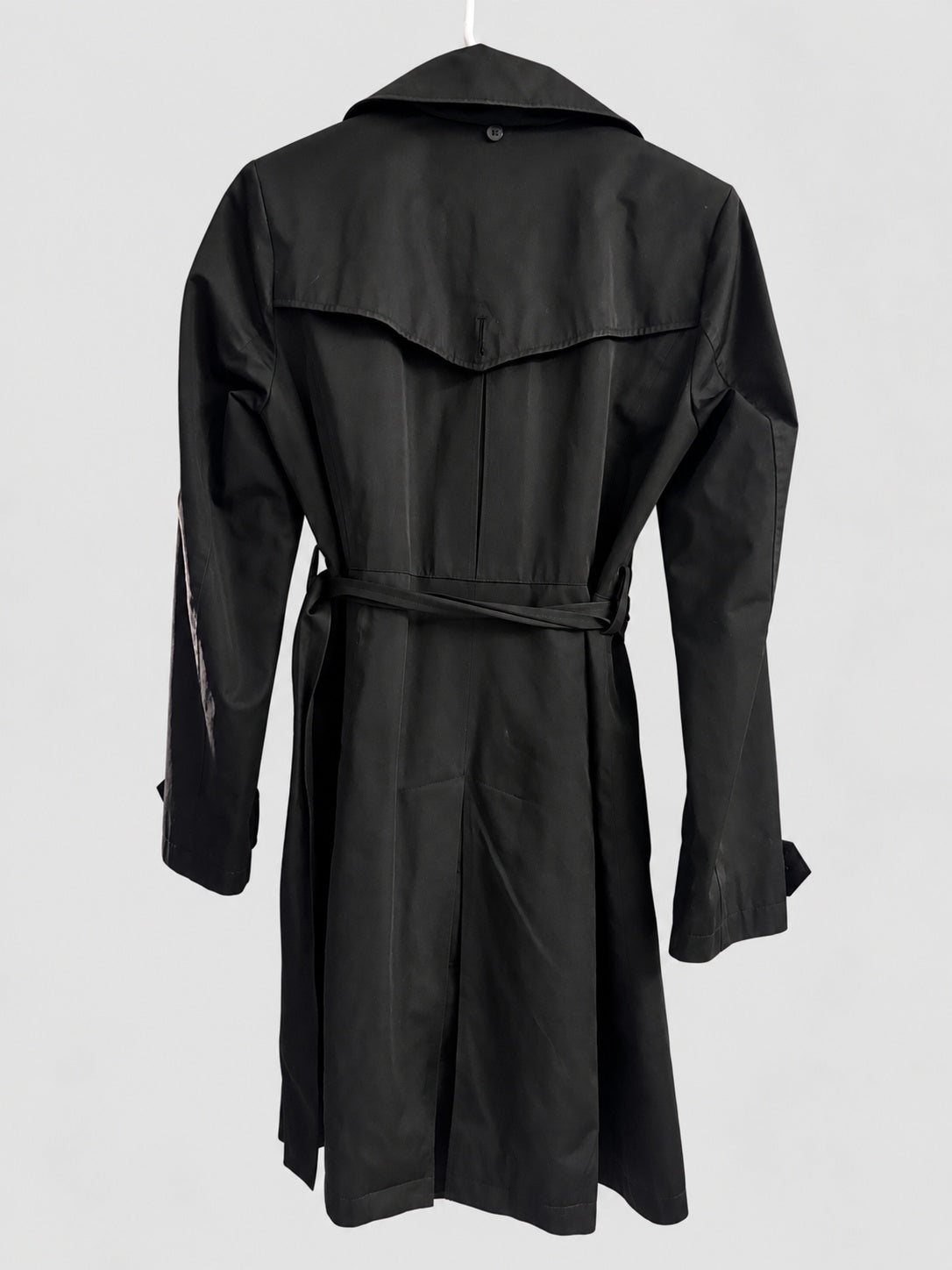 A black trench coat with a matching waist tie belt, shown from the back on a hanger against a light gray background.