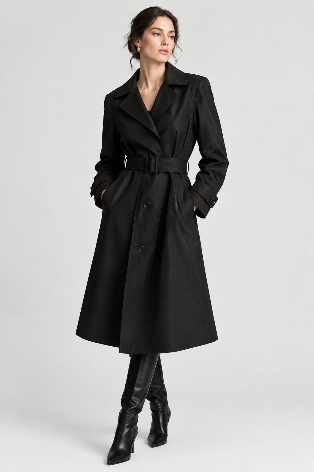 A black trench coat with a matching waist belt and dark buckle, hanging on a white hanger against a light gray background.