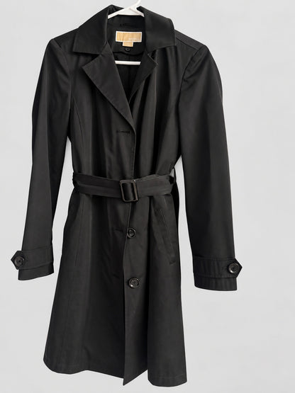 A black trench coat with a matching waist belt and dark buttons, displayed on a white hanger against a light gray background.
