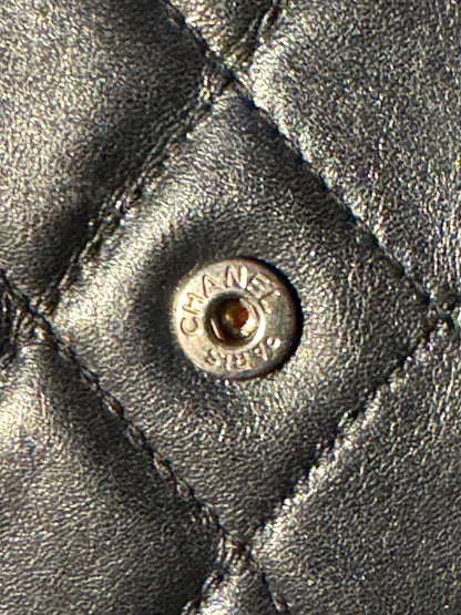 Close-up of a quilted black leather jacket with a silver-tone Chanel snap button.