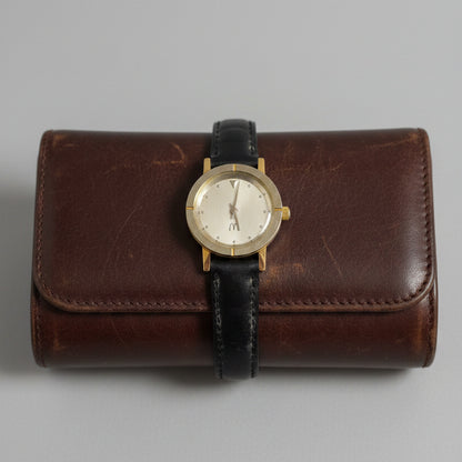 Wristwatch with black strap and gold case on a textured gray background