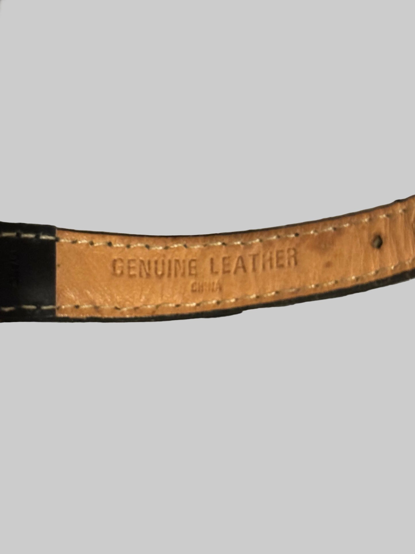 Close-up of a textured surface with a leather strap displaying 'Genuine Leather' text.