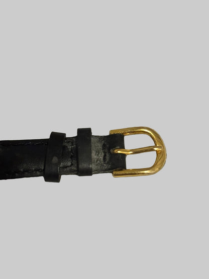 Black leather belt with a gold buckle on a textured gray background