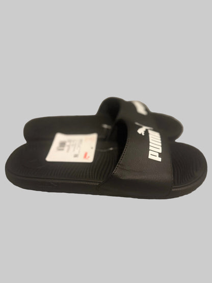 Black Puma slides with a label on a gray surface