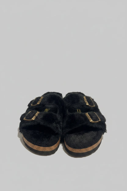 Pair of black slippers with soles on a textured surface