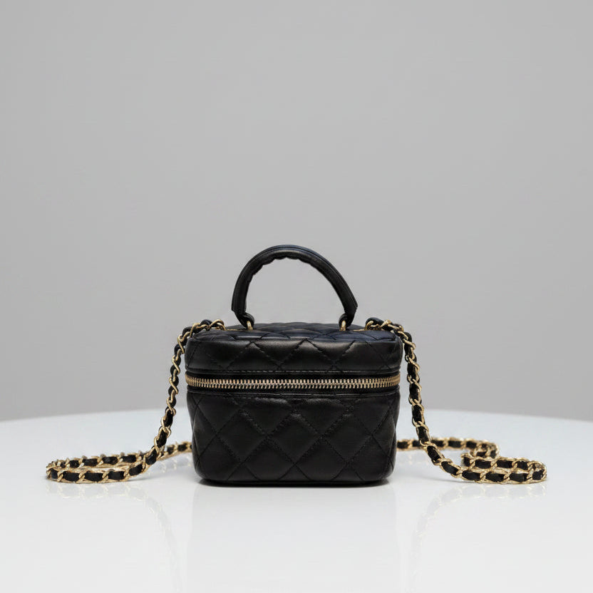 Black quilted handbag with a chain strap on a textured surface