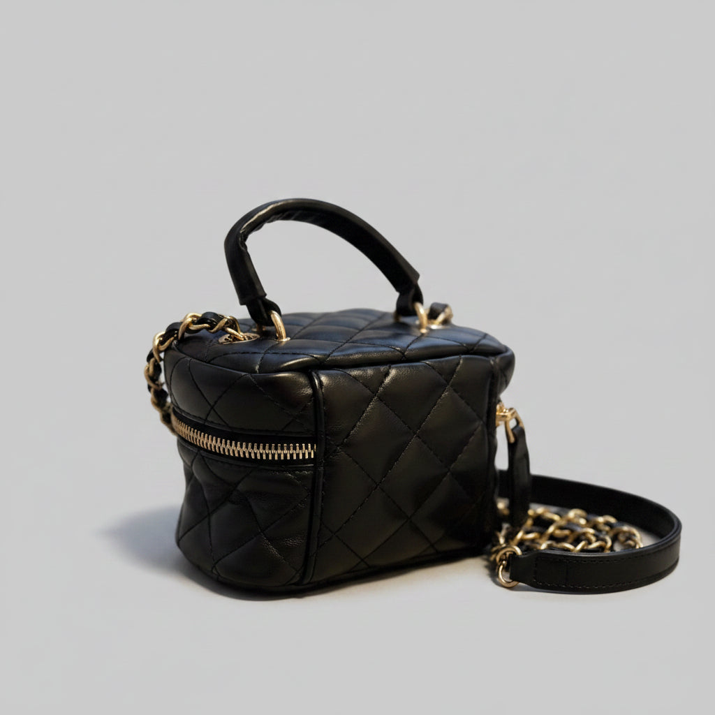 Black quilted handbag with gold accents on a textured surface