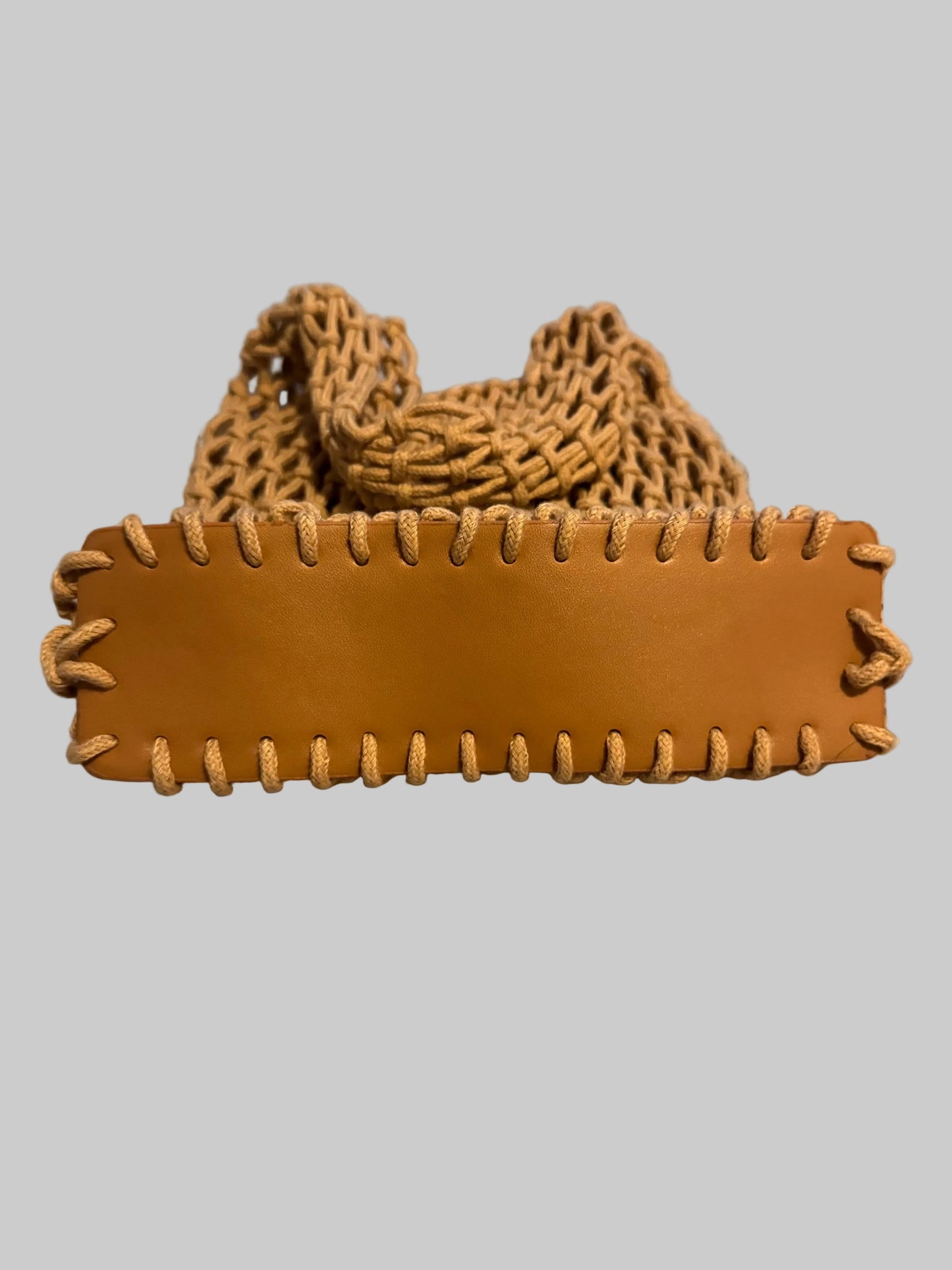 Brown leather belt with braided strap on a textured surface