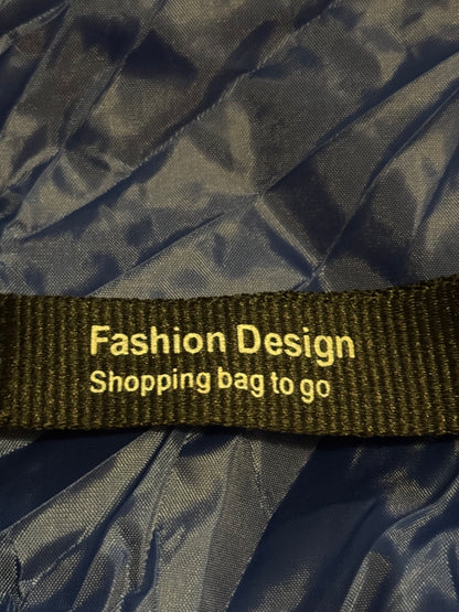 Black shopping bag with a green strap labeled 'Fashion Design Shopping bag to go' on a black background