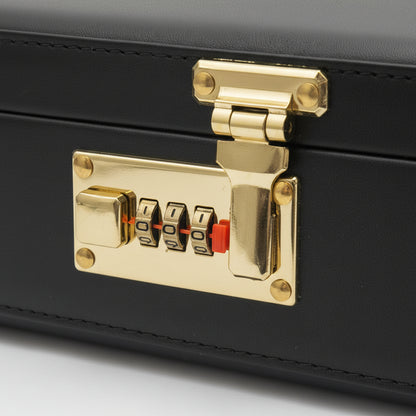Close-up of a black leather or faux-leather case with a shiny gold-tone combination lock and latch, resting on a wooden surface.