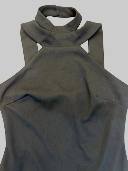 A black sleeveless halter-neck top with a wide collar and shoulder cutouts, laid flat on a brown wooden plank floor.