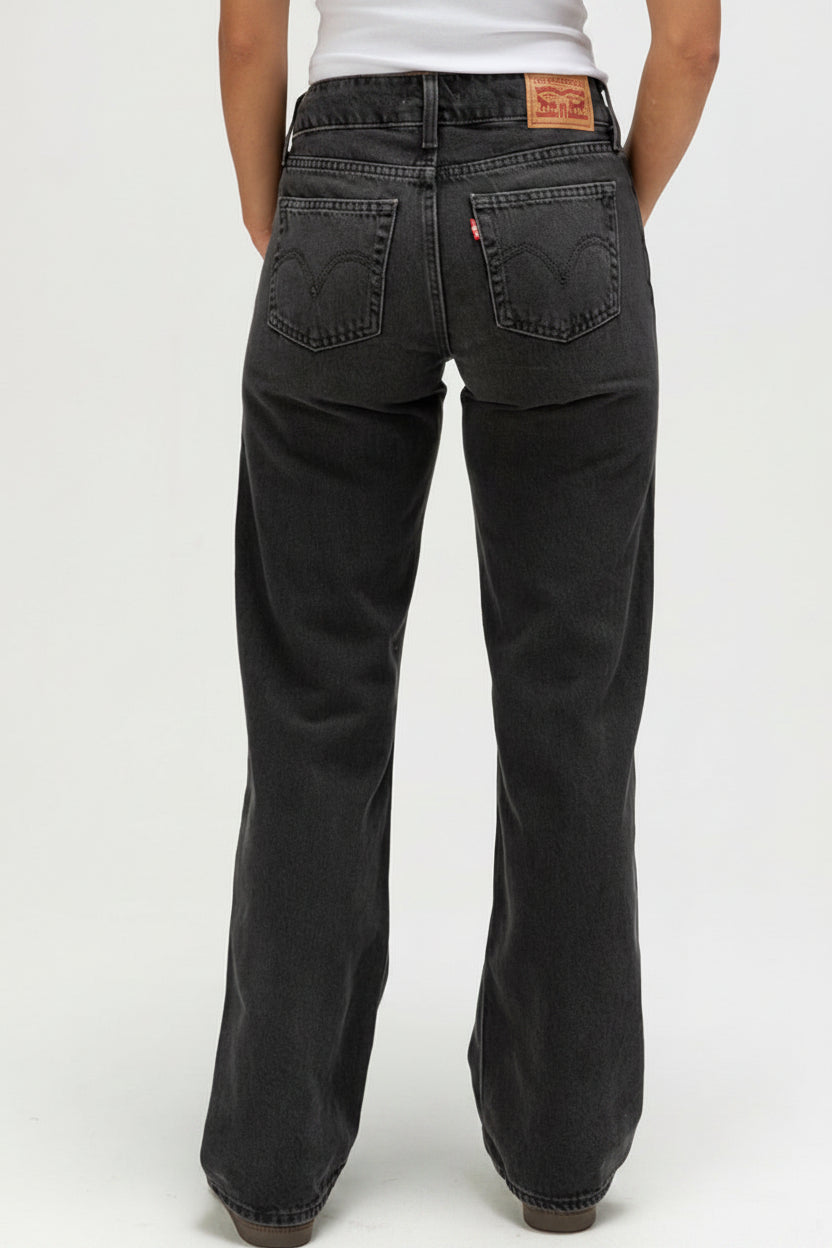Black jeans with a brand logo on the back pocket against a white background