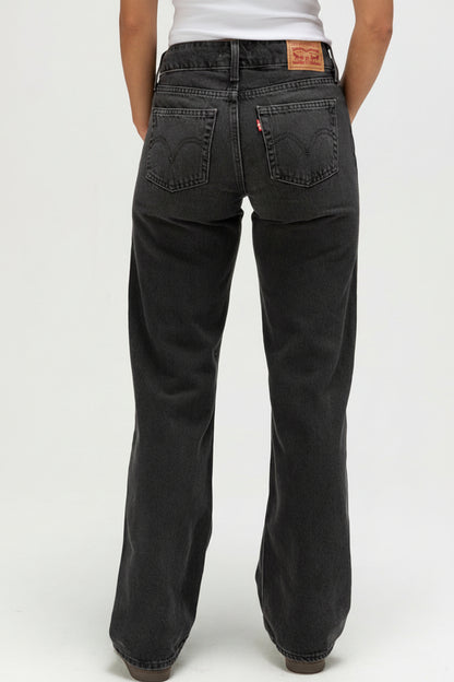 Black jeans with a brand logo on the back pocket against a white background