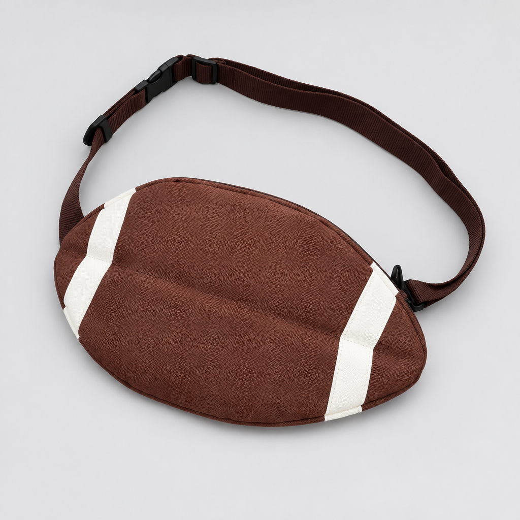 A football-shaped sleep mask with a brown faux-leather body, white stripes, and an adjustable dark strap, shown on a plain white background.