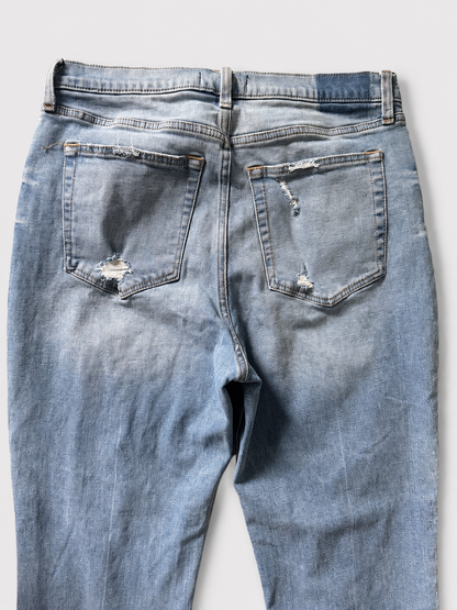 Light blue denim jeans shown from the back, featuring distressed rips on both back pockets and a faded wash.