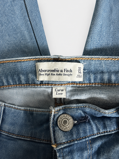 Close-up of blue denim jeans showing the inner waistband label for Abercrombie & Fitch, size 32 1/4, and a metal button at the front.