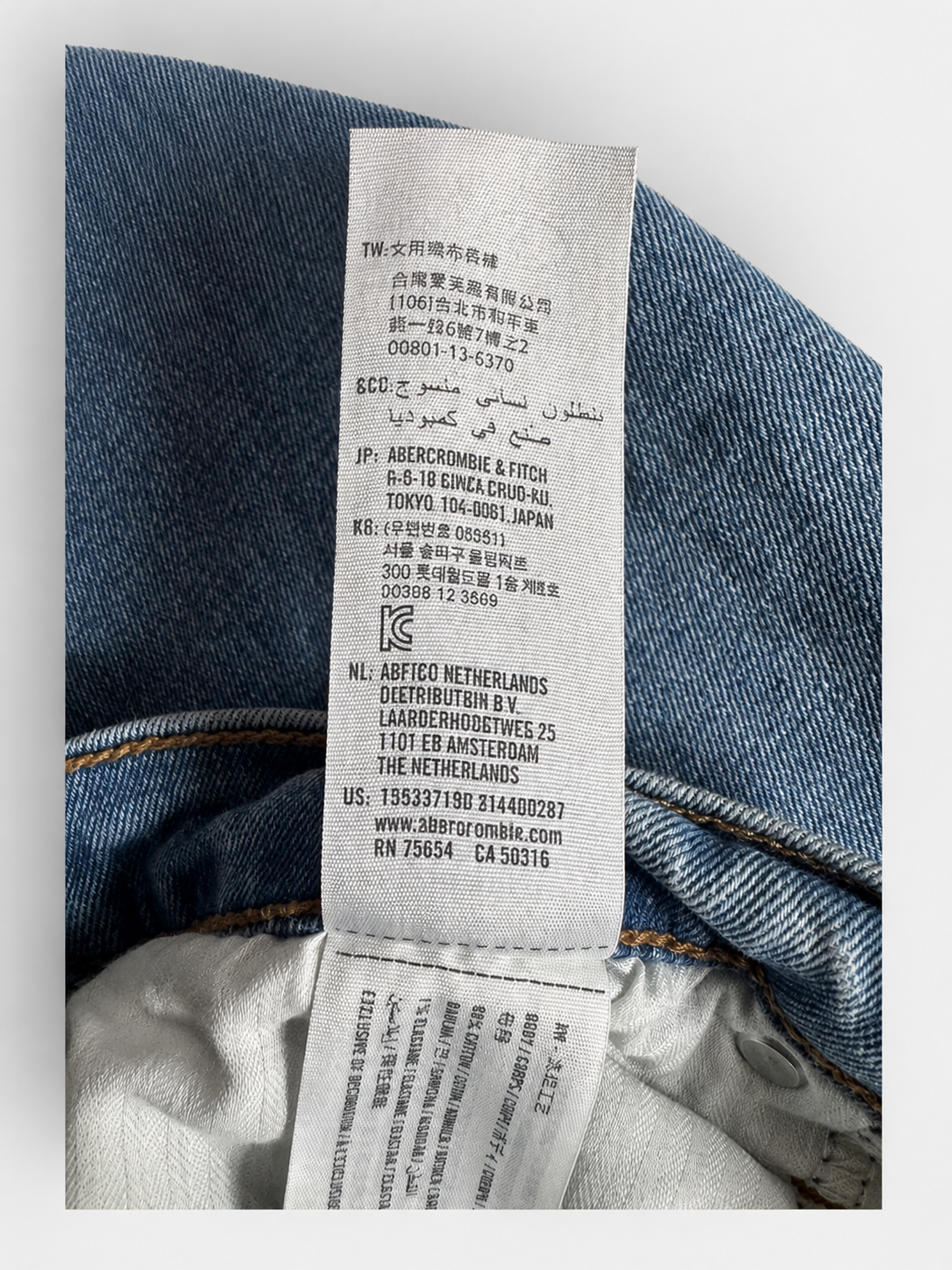 Close-up of a blue denim garment with a white sewn-in care label showing product details and branding.