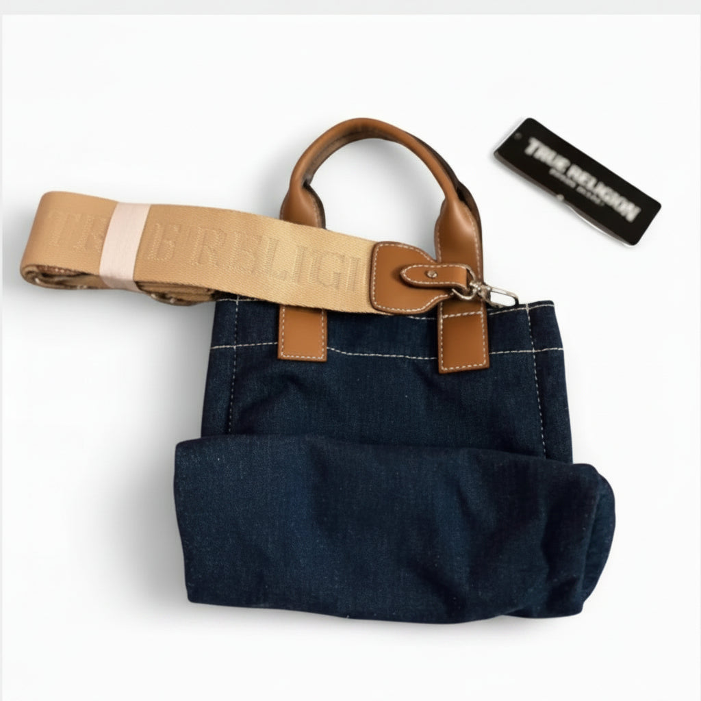 A dark blue denim tote bag with tan leather handles and trim, featuring a matching tan canvas shoulder strap with 'ERBLIG' text, shown on a white background with a black brand tag.