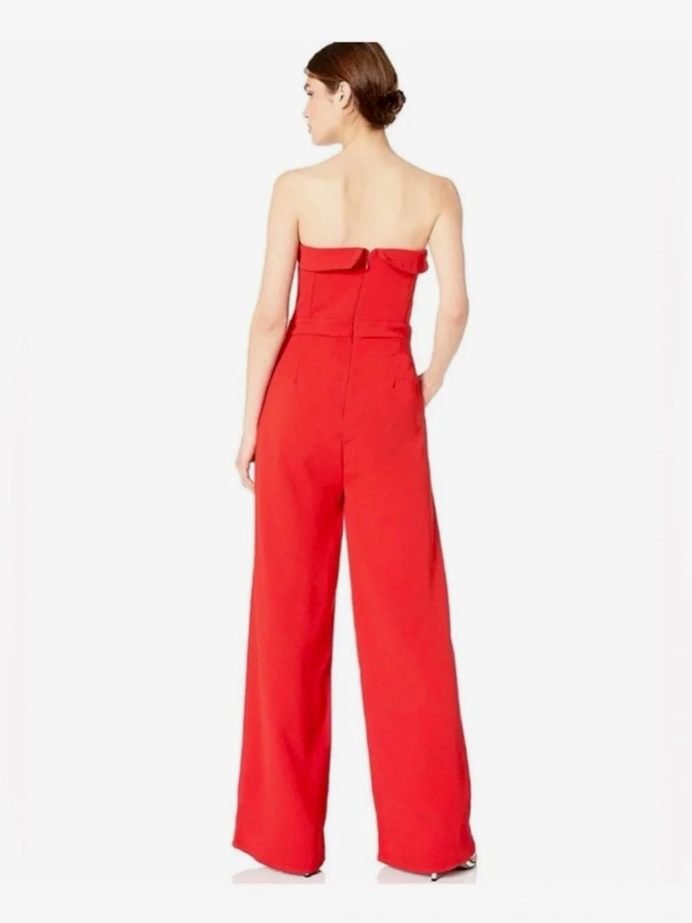 A woman modeling a bright red strapless wide-leg jumpsuit, shown from the back against a plain white studio background.