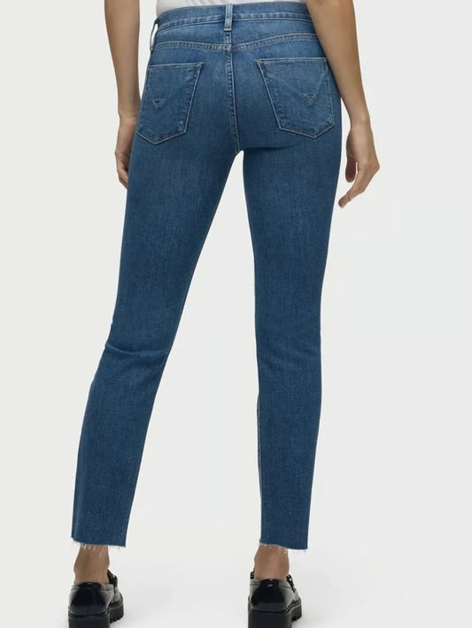 Rear view of a model wearing blue denim jeans with a straight-to-slim leg, showing the back pockets and hem, paired with black shoes against a light gray studio background.