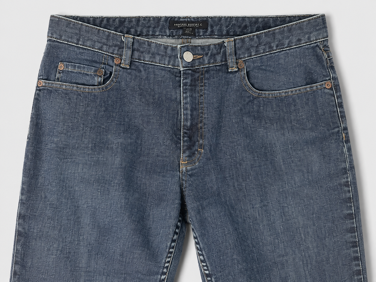 Close-up of a pair of blue denim jeans showing the front waistband, belt loops, button, and front pockets on a light gray background.