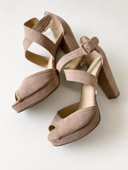 A pair of women's platform block-heel sandals in a dusty taupe suede-like material, featuring open toes, double crossover straps, and adjustable ankle straps, shown on a light off-white background.